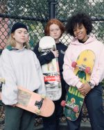 Potrait aufnahme von 3 jungen Frauen. Aly, Aggie and Malaika posieren mit Ihren Skateboards vor einem Zaun