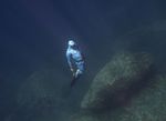 The freediver rises from the bottom of the sea near underwater rocks