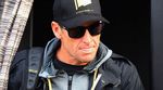 Retired cyclist, Lance Armstrong, wearing a black jacket, baseball cap, and dark sunglasses
